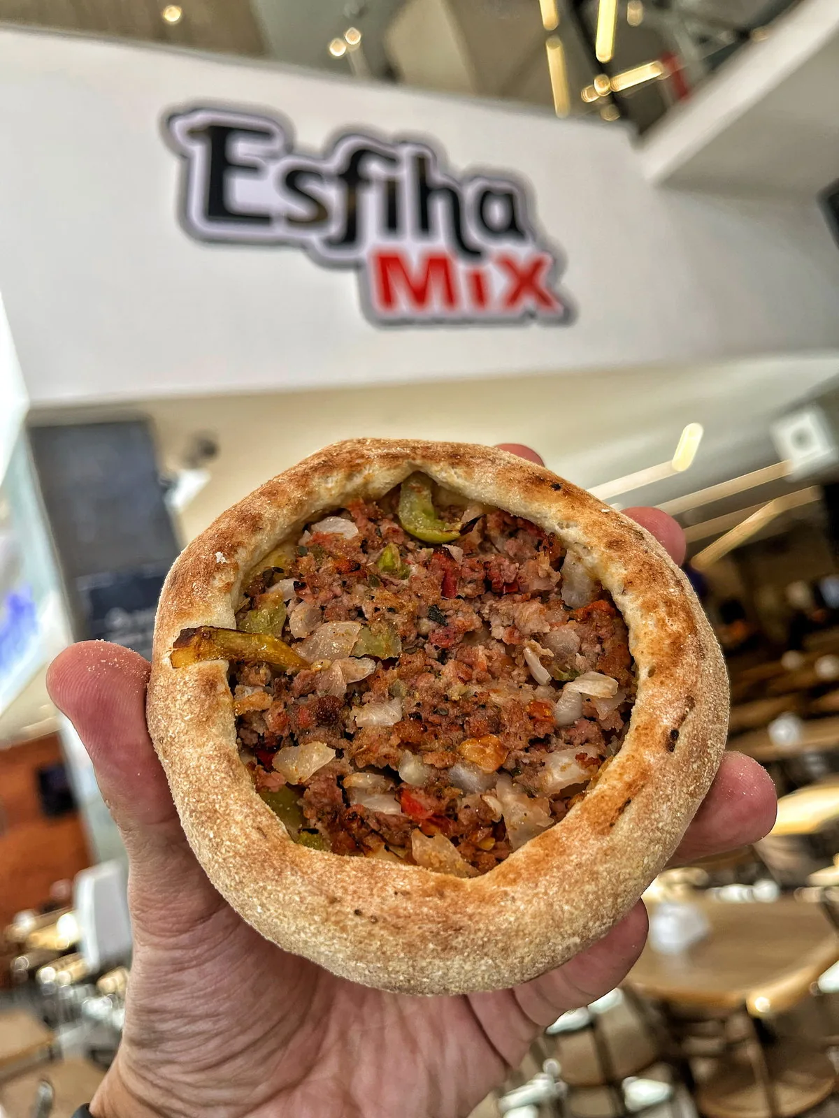 Esfiha de carne segurada dentro de uma unidade Esfiha Mix